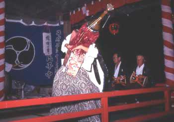 竹かごを芯にしたかまきりのかぶりものをかぶり、 4枚の羽根を背負った人の写真