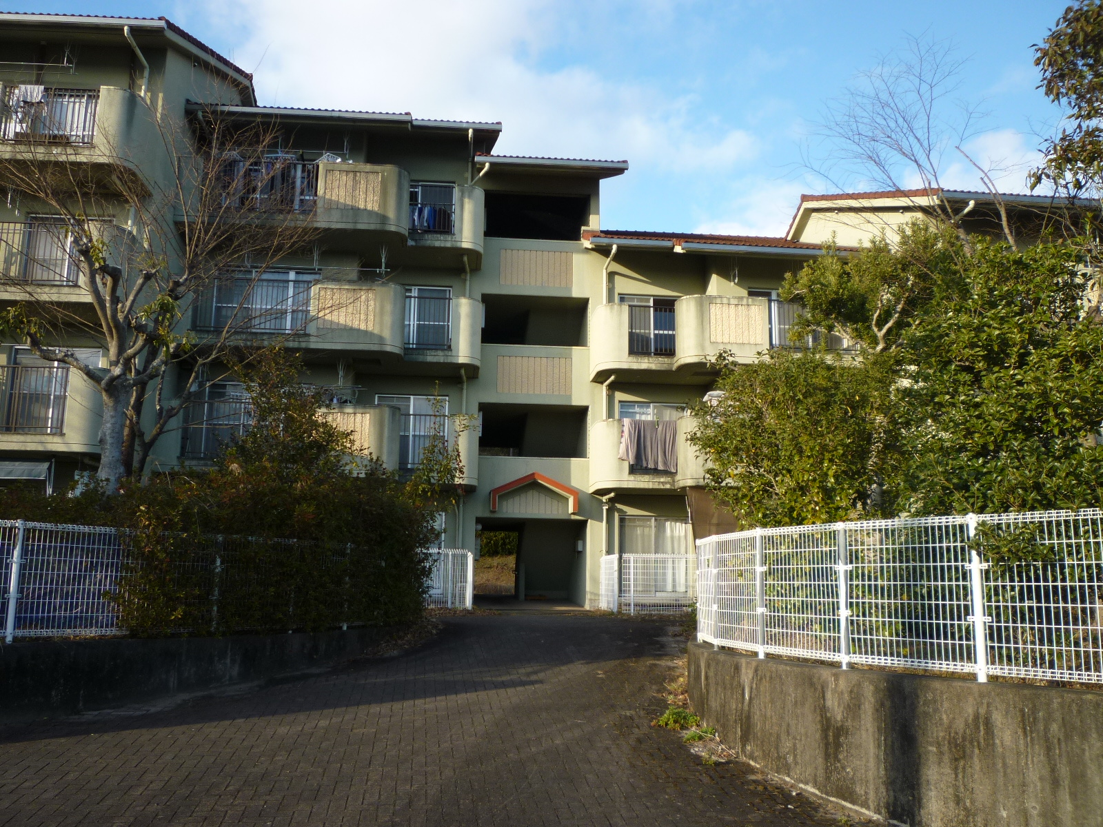 3階、4階建て、緑に囲まれた薄緑色の建物の町営住宅やざき団地の写真