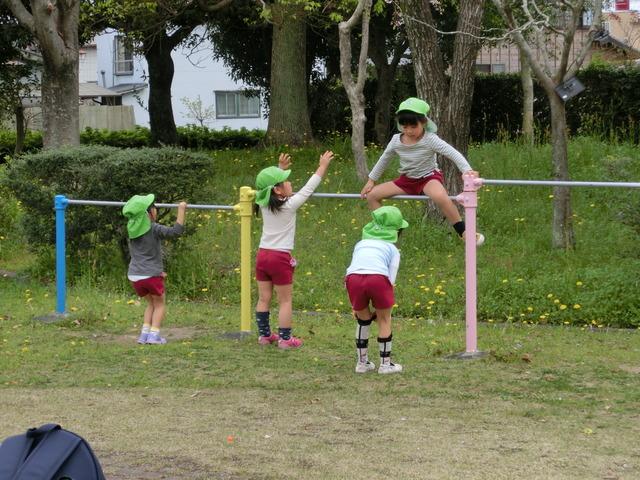 第2公園で、体操着と黄緑色の帽子をかぶり鉄棒遊びをしている園児たちの写真