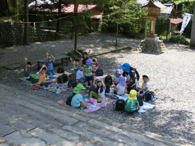 天宮神社の境内で、階段の近くにそれぞれがシートを敷き、両手を上げたりポーズをとっている写真