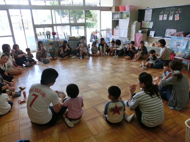 教室で保護者と隣合わせで、大きな輪になって座っている園児たちの写真
