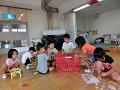 施設内で児童たちが座って、おもちゃで遊んでいる写真